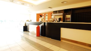 A hotel reception area with a counter, shelves with items, and a tiled floor.