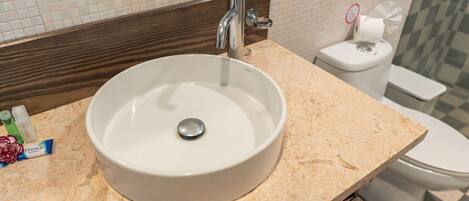 A bathroom with a white sink, a mirror, and a toilet.
