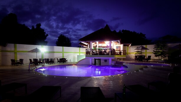 A pool area with lounge chairs and a bar area with umbrellas.