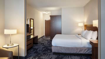 A hotel room with a large bed, a desk, a chair, a mirror, and a lamp.