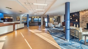A spacious lobby with a reception desk, seating area, and a stone fireplace.
