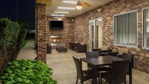 An outdoor patio with stone walls, a fireplace, and seating areas.