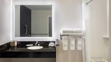 A modern bathroom with a black countertop, a white sink, a large mirror, and a shower curtain.