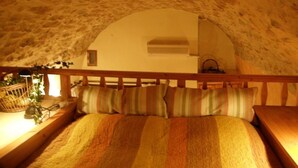 Een knus slaapkamer met een schuine kap, een houten hoofdbord, en een bed met gestreept beddengoed.