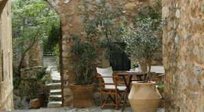 Un espace extérieur aménagé dans un style rustique, avec des murs en pierre, des chaises en bois et des plantes en pot.