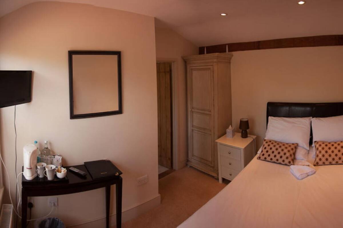 A hotel room with a bed, a bedside table with a lamp, a wardrobe, and a television on a stand.