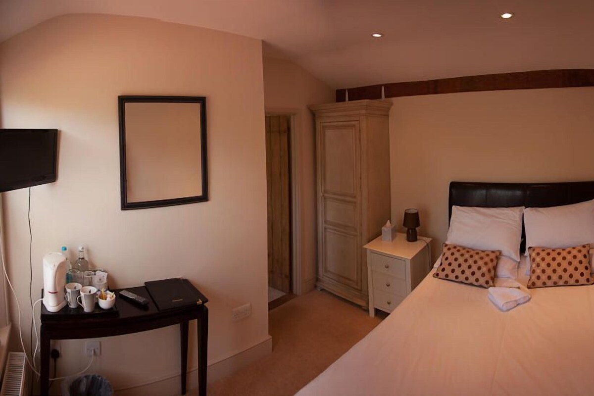 A hotel room with a bed, bedside table, and a wardrobe.