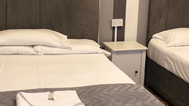 A hotel room with two beds, a nightstand, and a power outlet.