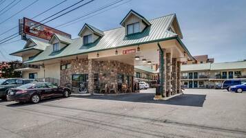 A motel with a stone facade, a covered parking area, and a sign indicating '10th Clearance'.