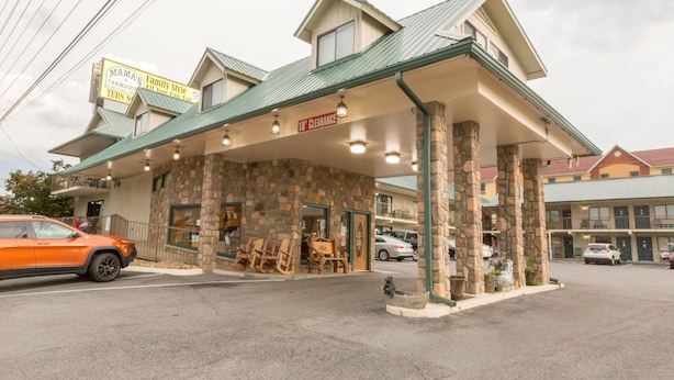 A motel with a stone facade, a covered parking area, and a sign indicating a 10' clearance. - Mountain Breeze Motel (Pigeon Forge)