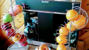 A kitchen counter with a Bunn coffee maker, a box of Krispy Kreme, and fruit skewers. - Mountain Breeze Motel (Pigeon Forge)