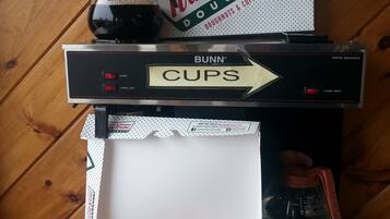 A box of Krispy Kreme doughnuts with a sign for the Bunn coffee maker and a coffee pot.