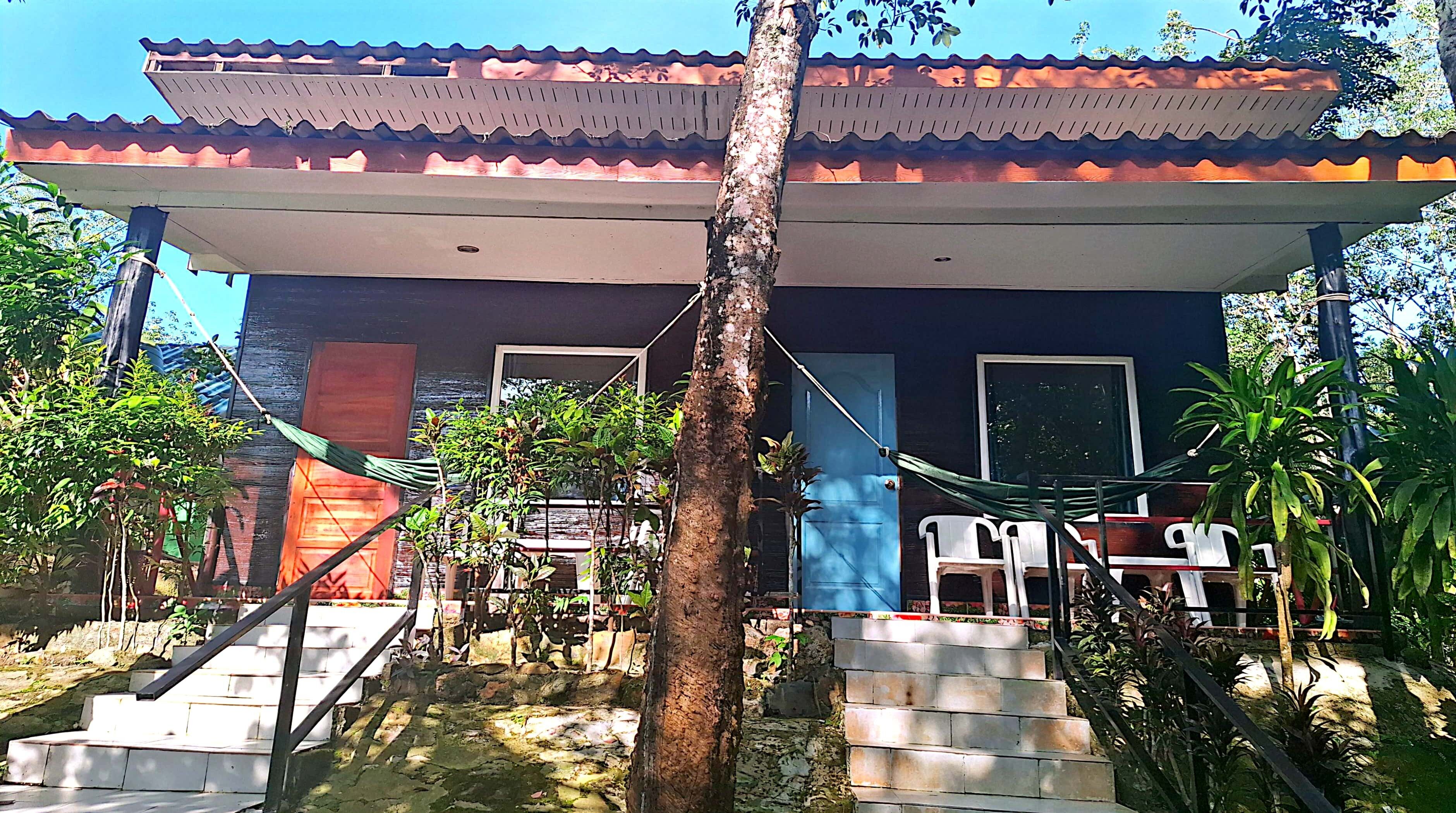 A building with a tiled roof, a staircase leading to a porch, and outdoor seating.