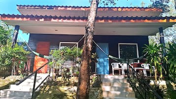 Um edifício com telhado de cerâmica, escadaria que leva a um alpendre e área de estar externa.