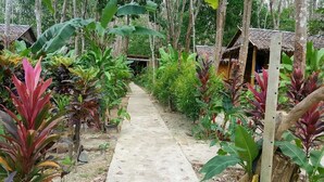A pathway leading to thatched-roof huts surrounded by lush greenery and tropical plants. - Lanta Maikeaw Bungalow (Ko Lanta)