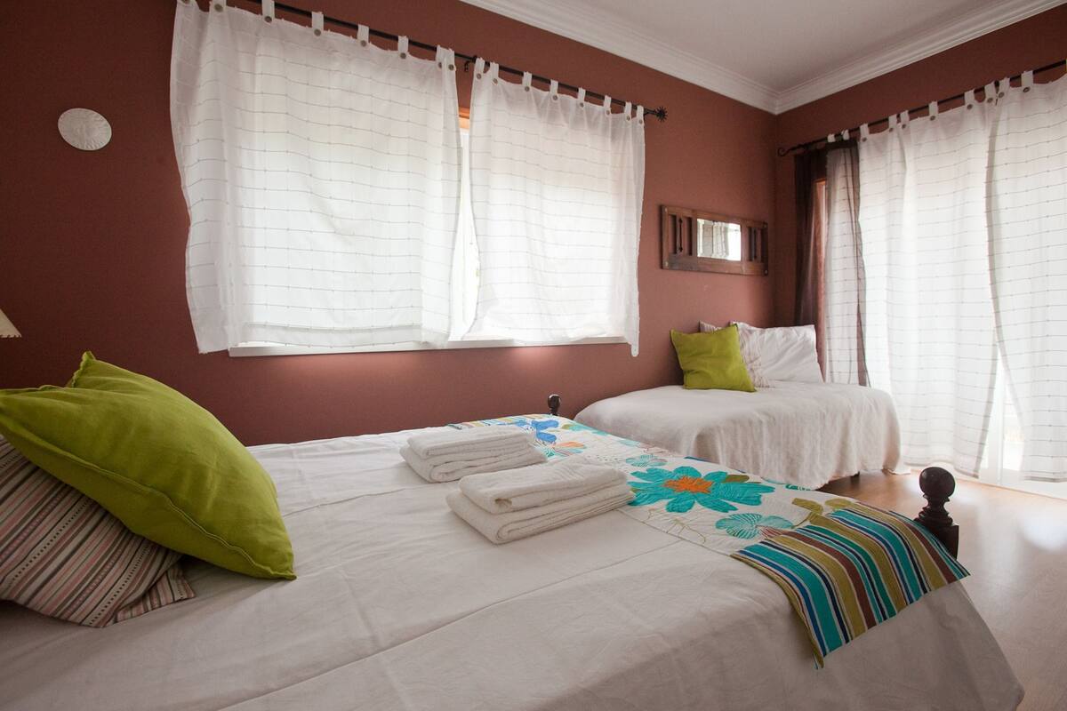 A hotel room with two beds, white bedding, and a green pillow.