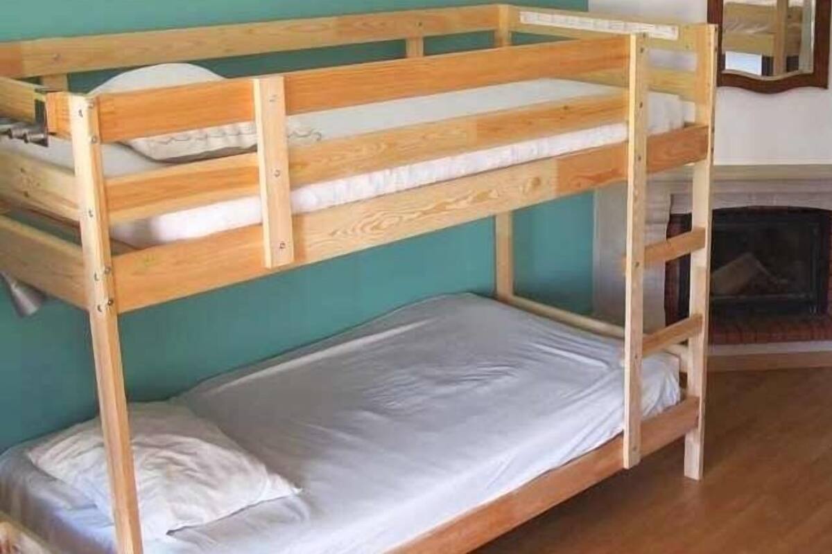 A room with two bunk beds, a fireplace, and teal walls.