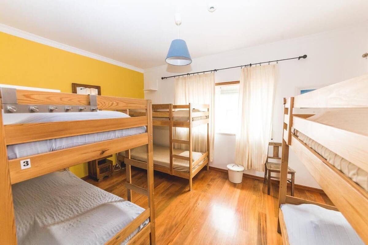 A bunk bed room with wooden bunk beds, a small table, and a blue hanging light fixture.