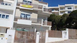 Un immeuble résidentiel à plusieurs étages, doté de balcons, d’une entrée sécurisée et surplombant un ciel d’un bleu éclatant.