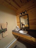 Un baño con tocador de madera, un lavamanos blanco y un espejo.