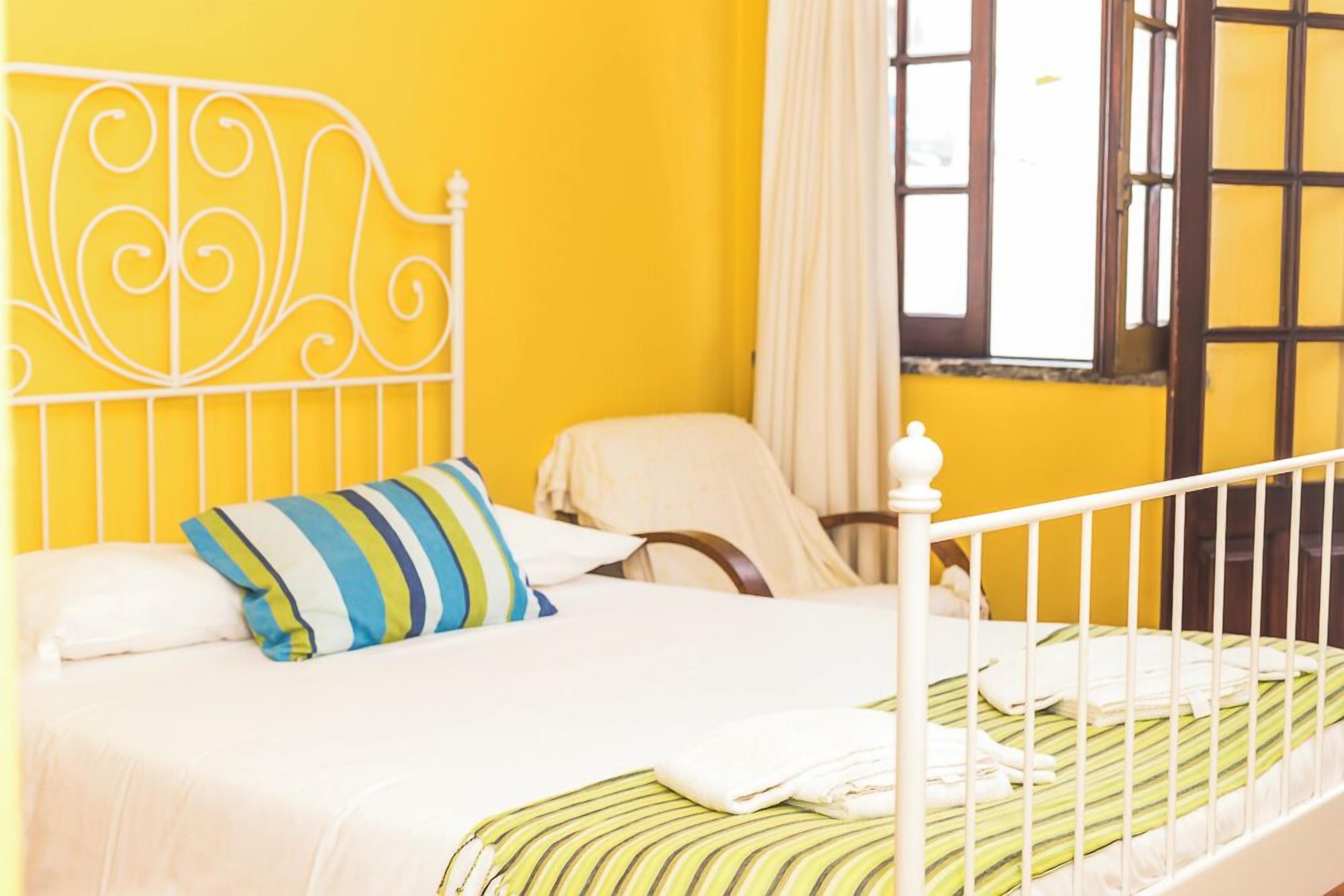 A bed with a white metal headboard, a striped pillow, and a green-striped bedspread.
