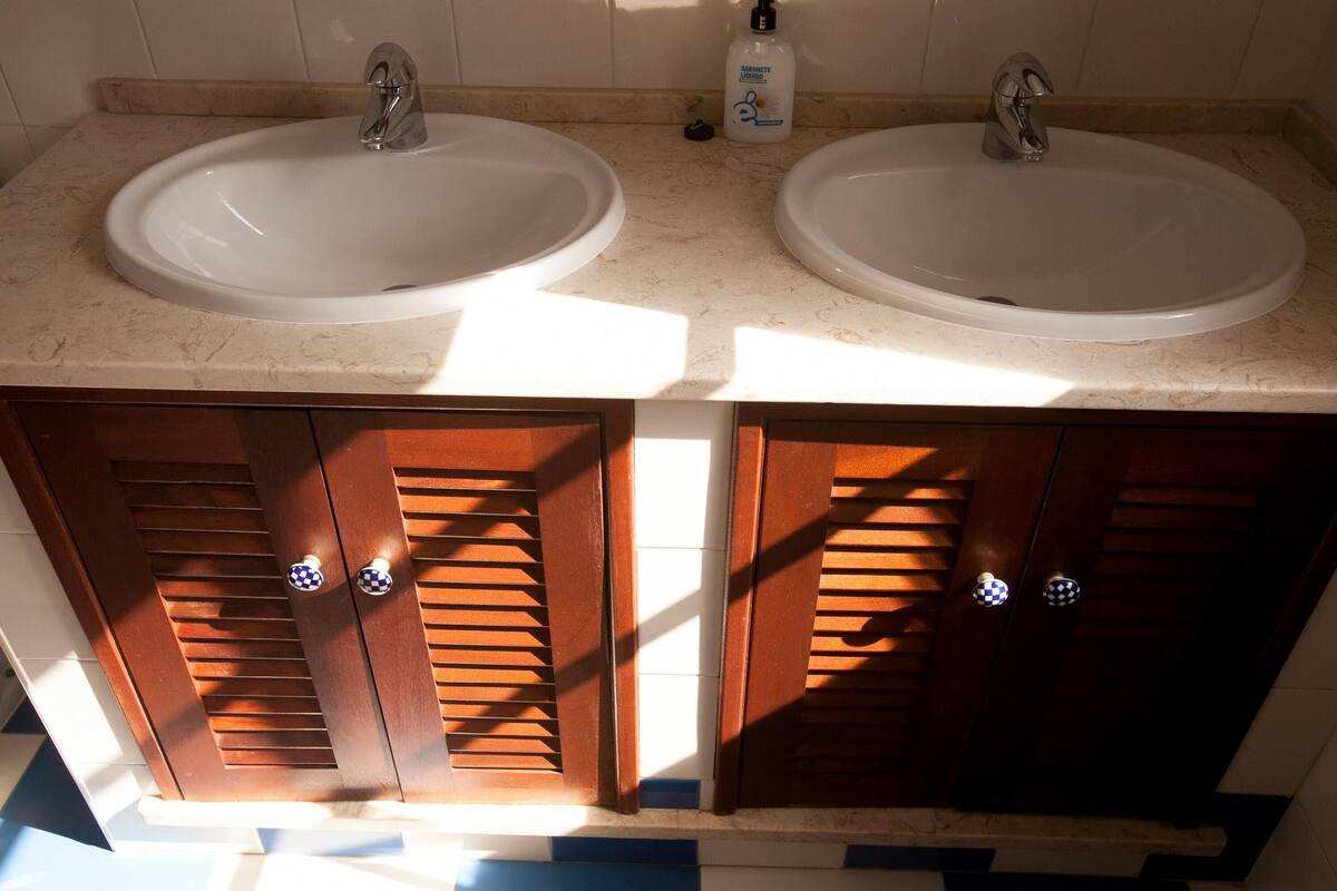 A bathroom with two sinks, wooden cabinets, and a bottle of hand soap.