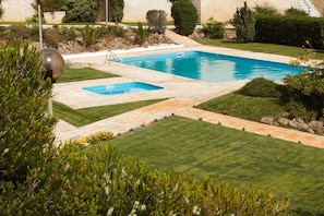 Piscina retangular com plataforma de mergulho, rodeada por gramados bem cuidados e arbustos variados.