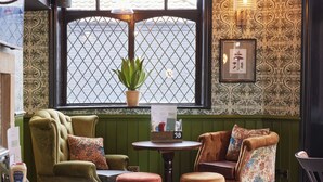 A cozy room with green paneled walls, a window with a plant, and a table with a menu.