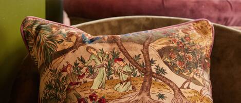 A close-up of a cushion with a detailed illustration of a scene with trees and figures.