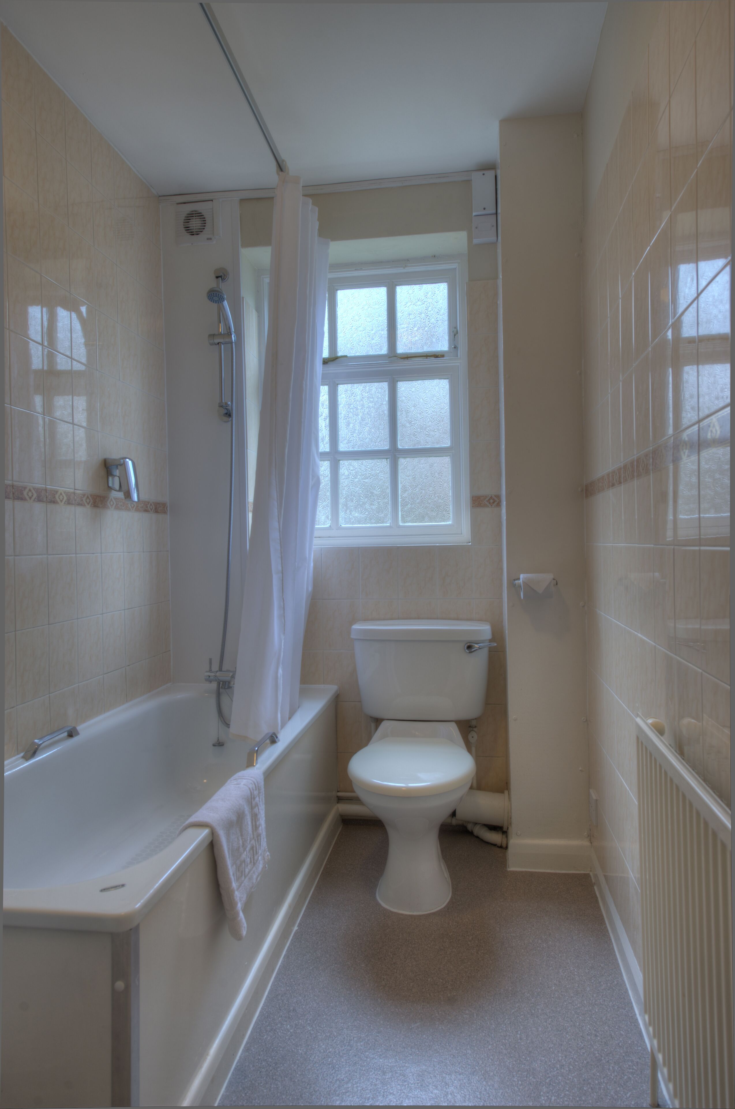 Ein Badezimmer mit Badewanne, Toilette und einem Fenster.
