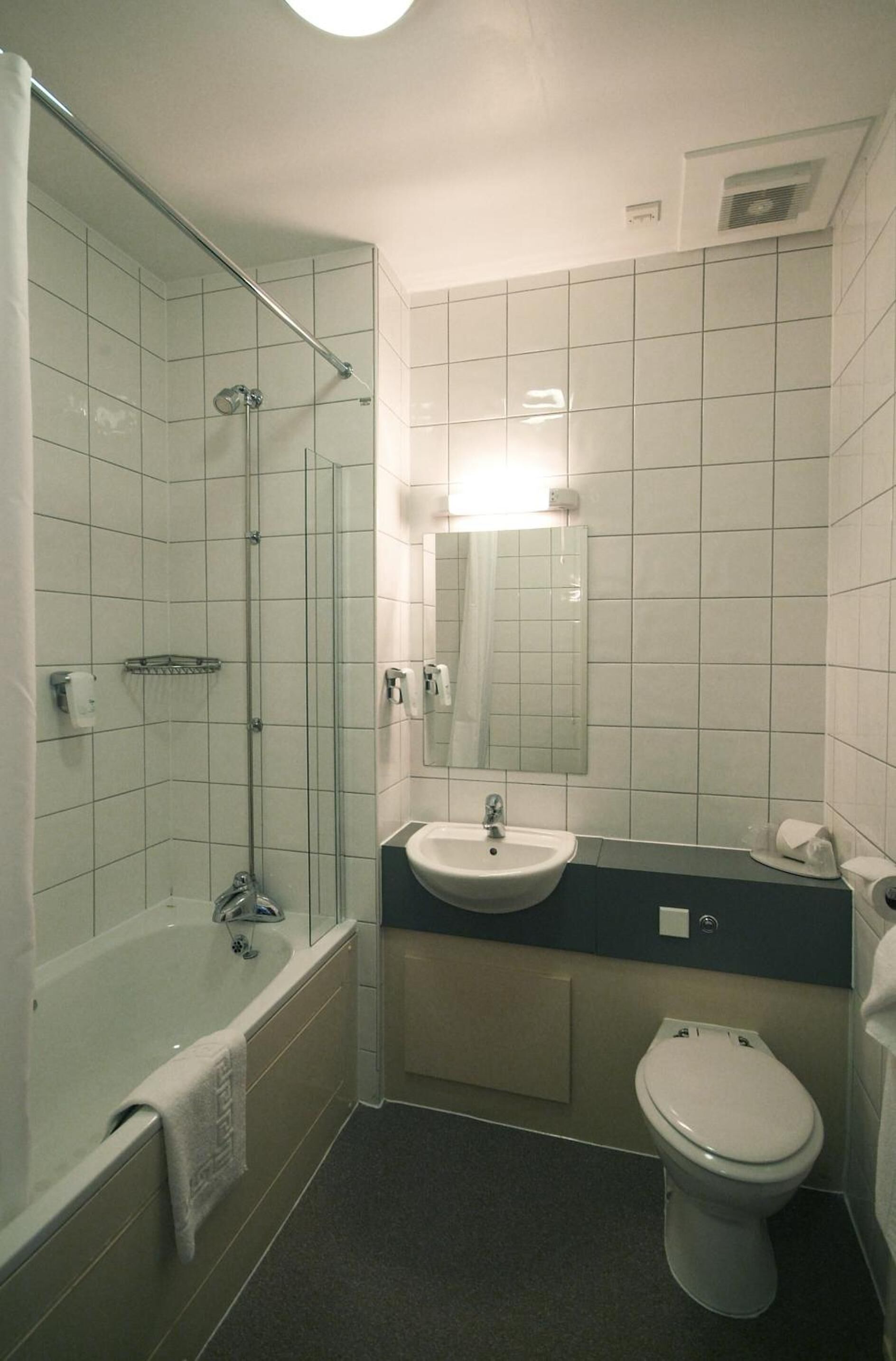 Un bagno con doccia vetro, lavandino e servizi igienici.