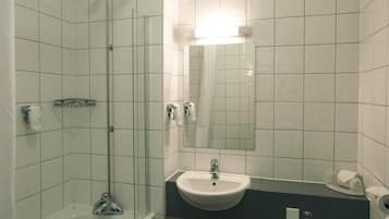 Un bagno con doccia vetro, lavandino e servizi igienici.