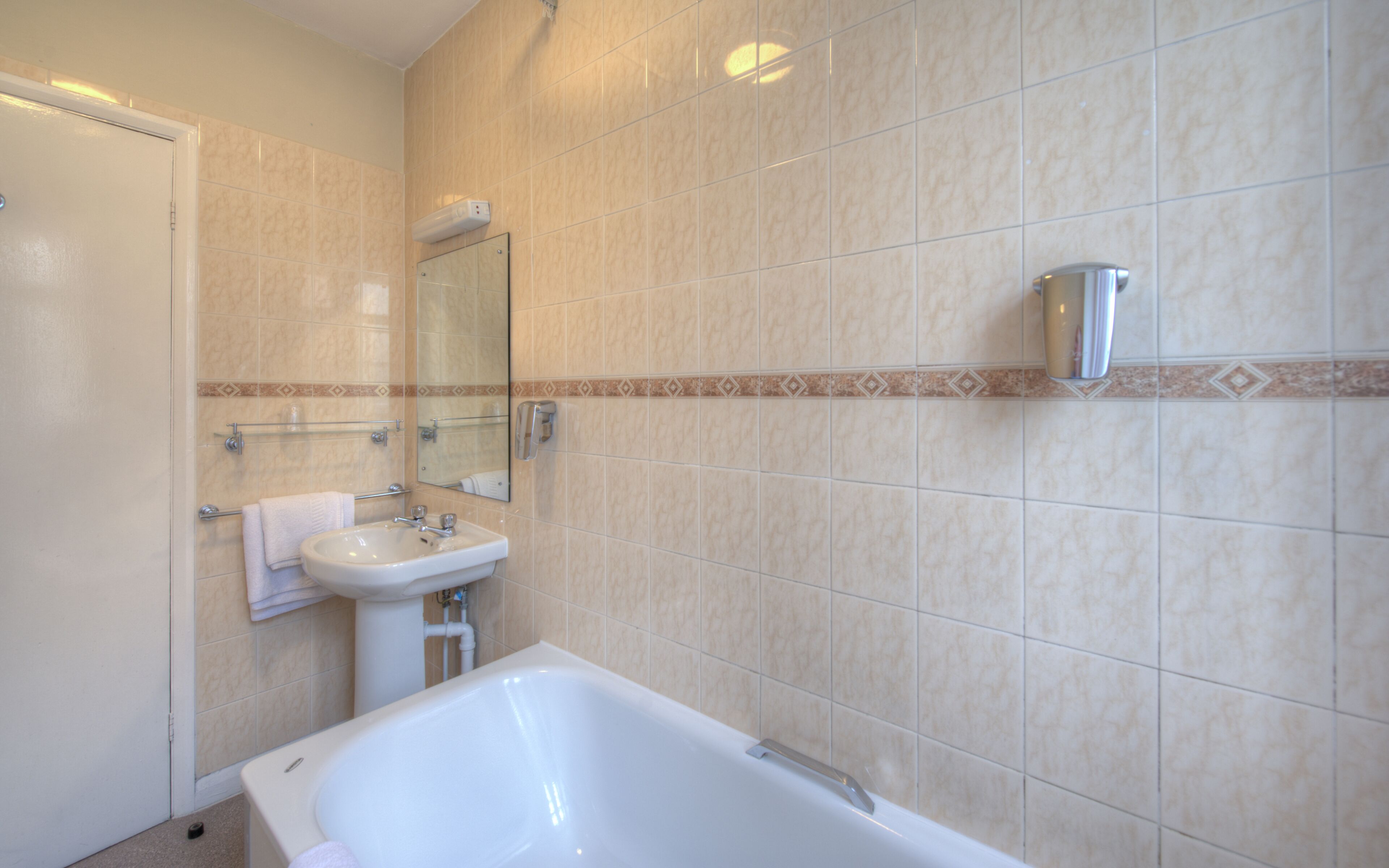 A bathroom with a bathtub, sink, and mirror.
