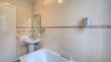 A bathroom with a bathtub, sink, and mirror.