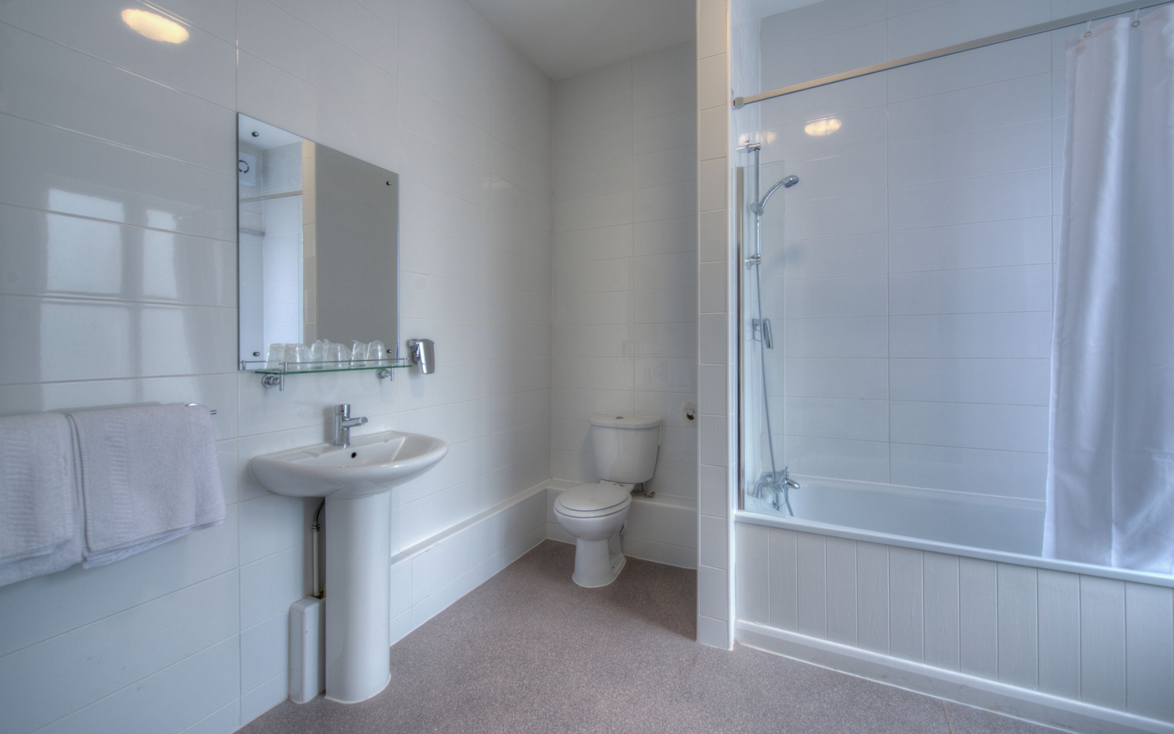 A bathroom with a sink, toilet, and glass shower enclosure.