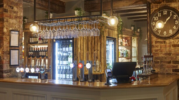 A bar area with a wine cooler, multiple beer taps, and a clock on the wall.