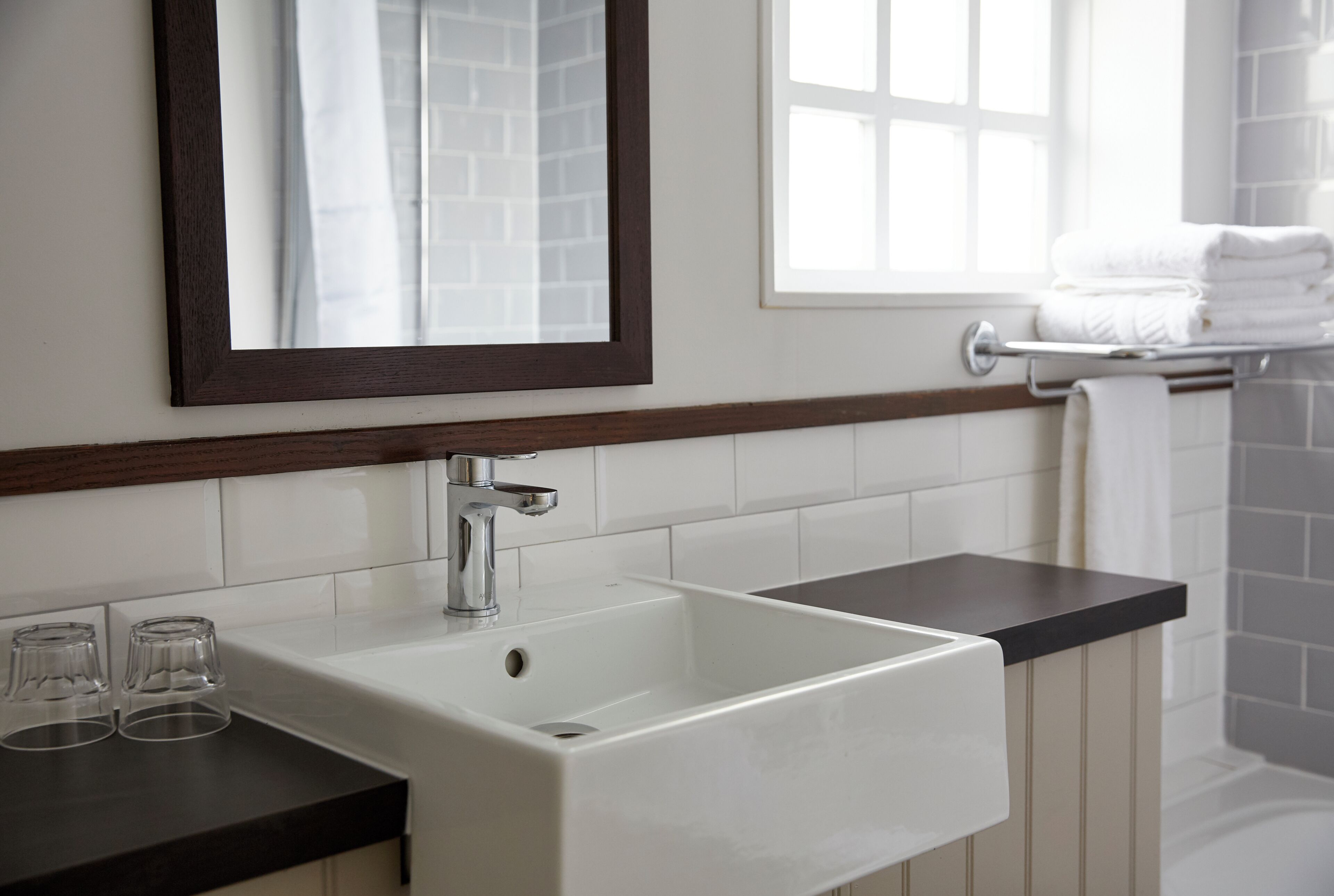 A bathroom with a white sink, a mirror, and a window.