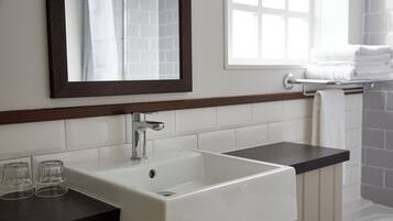 A bathroom with a white sink, a mirror, and a window.