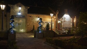 A stone building with a 'Welcome' sign, a Christmas tree, and outdoor seating area.