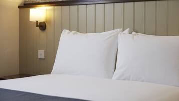 A hotel room with a bed, a wall-mounted light, and a textured wall design.