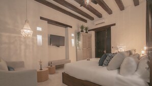 A modern bedroom with a large bed, a TV, a chandelier, and a plant. - Casa Gastelbondo By Vistamarina - Adults Only (Cartagena)