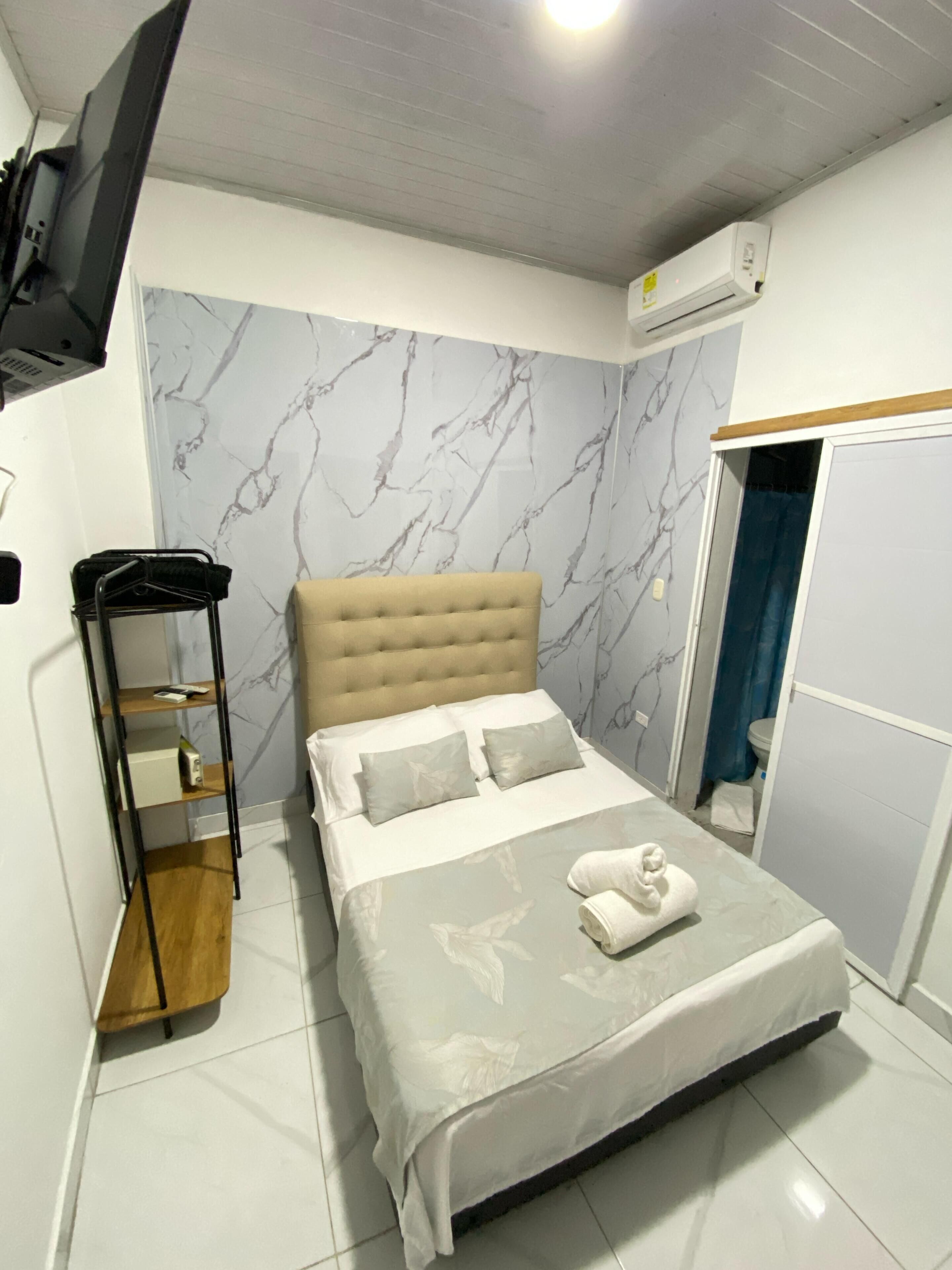 A bedroom with a bed, a TV mounted on the wall, and a wardrobe.