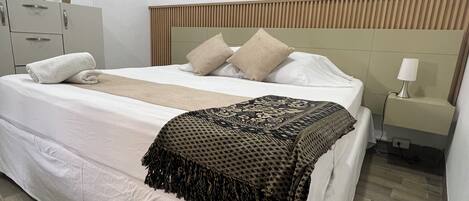 Een hotelkamer met een bed, nachtkastje, lamp, airconditioning en een kledingkast.