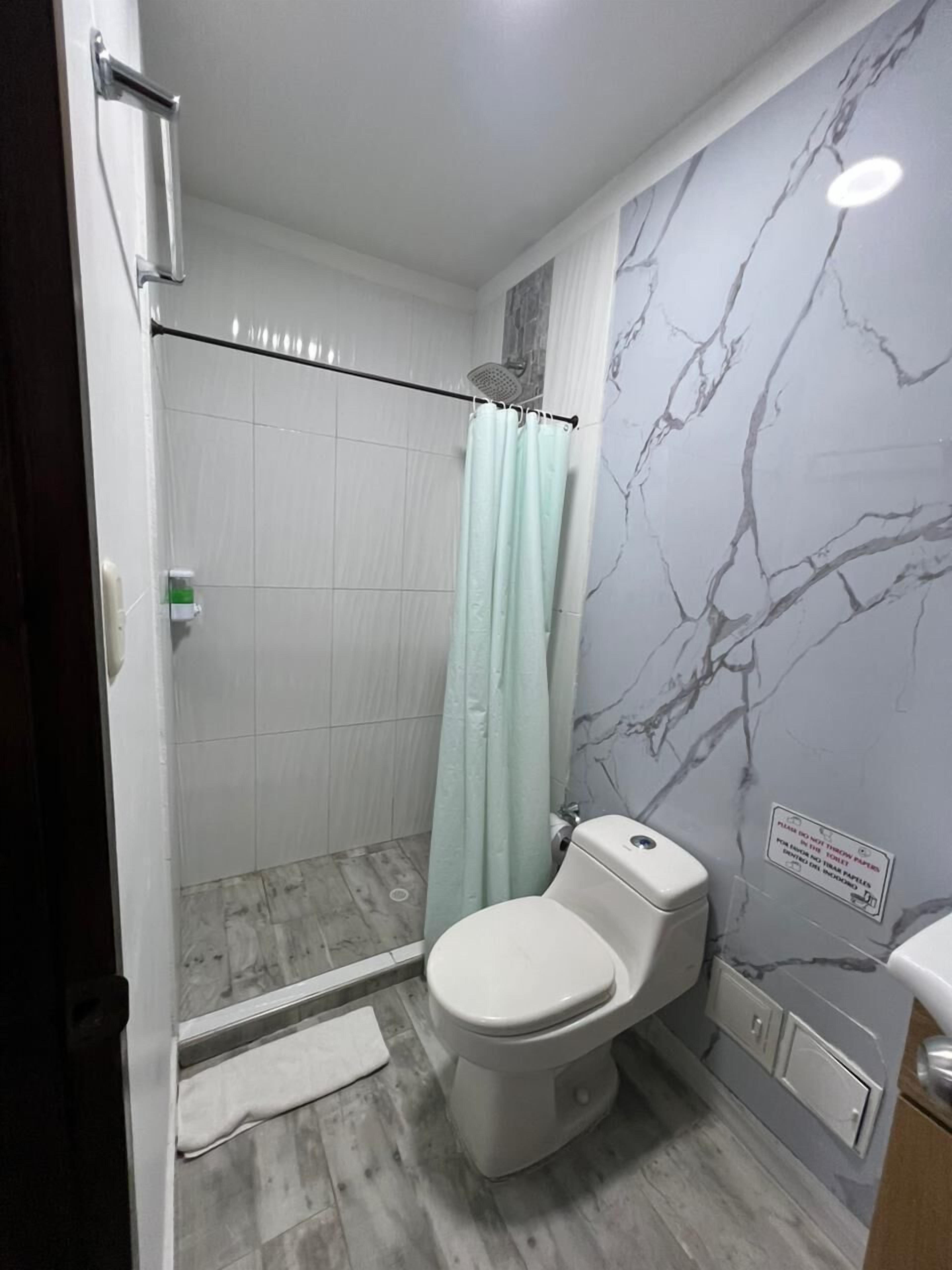 A bathroom with a shower, toilet, and marble-patterned walls.