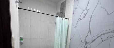 Un baño con ducha, inodoro y paredes con diseño de mármol.