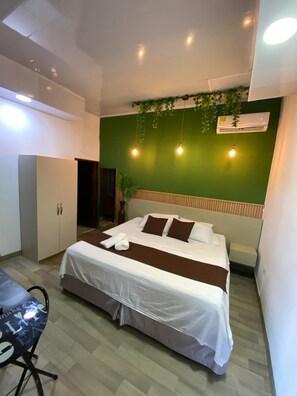 Habitación de hotel moderna con cama, armario, escritorio y pared verde.