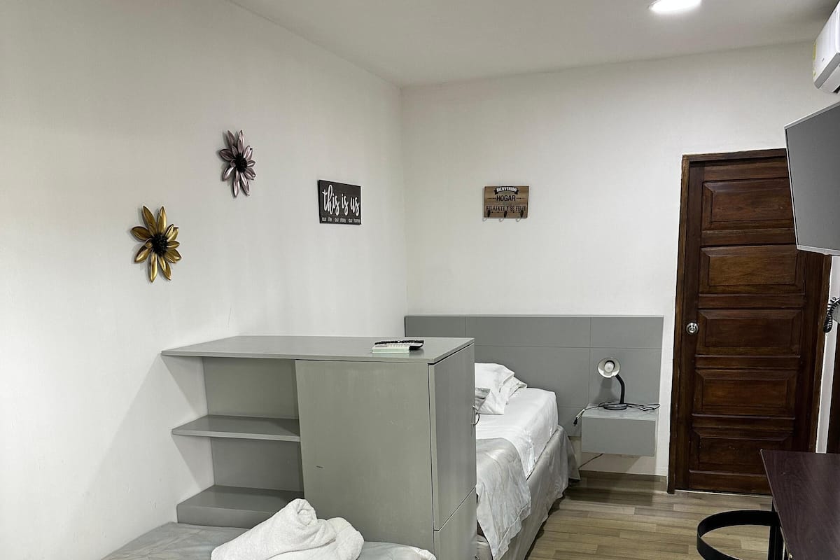 A hotel room with two single beds, a desk, and a chair.