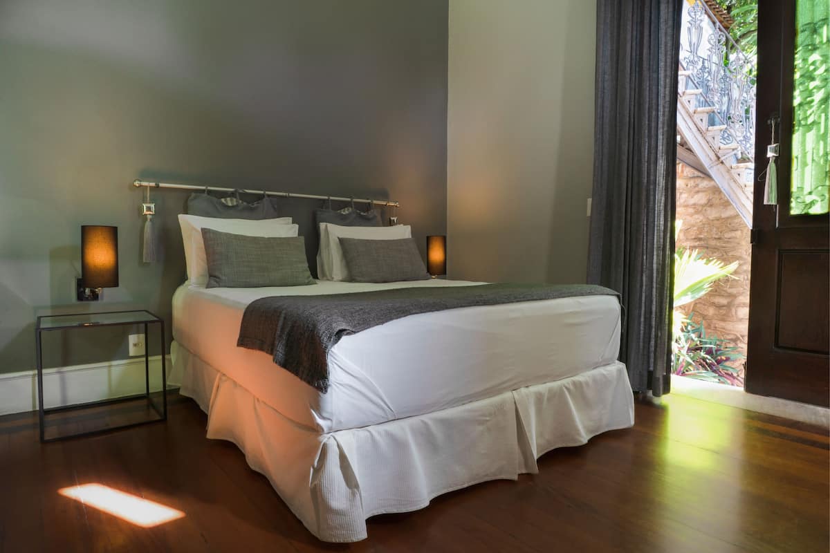 Ein Schlafzimmer mit Bett, Nachttischen und Blick auf einen Balkon.