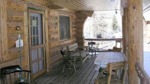 A wooden cabin with a covered porch, a dining table, and chairs. - Scandanavian Vacation Rental (Lake City)