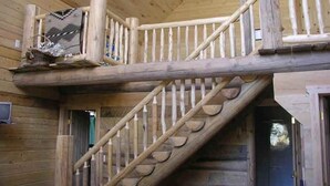 Una escalera de madera con barandilla que lleva a un balcón.
